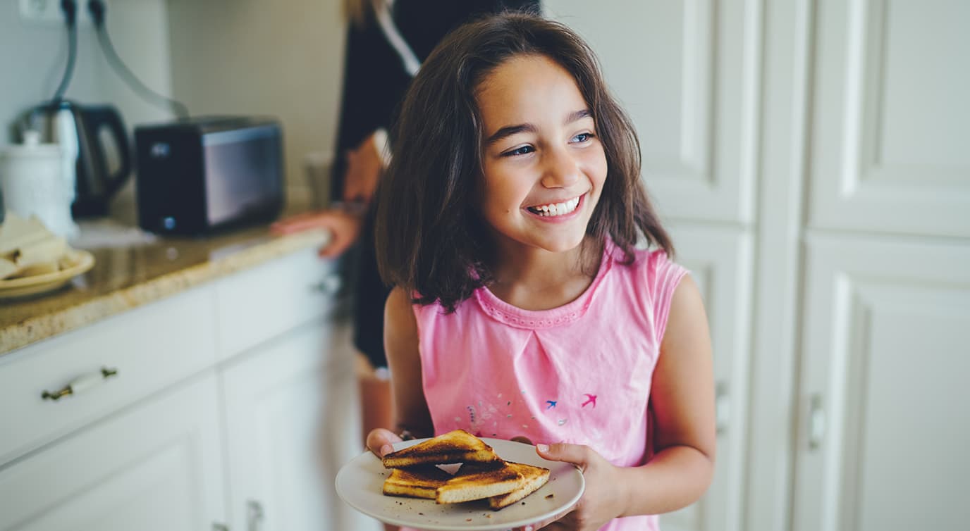 Little girl holding a plate of grilled cheese